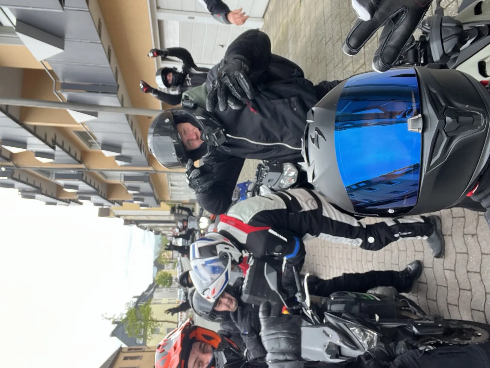 Lachende motorrijders met helmen op in een Duits dorp
